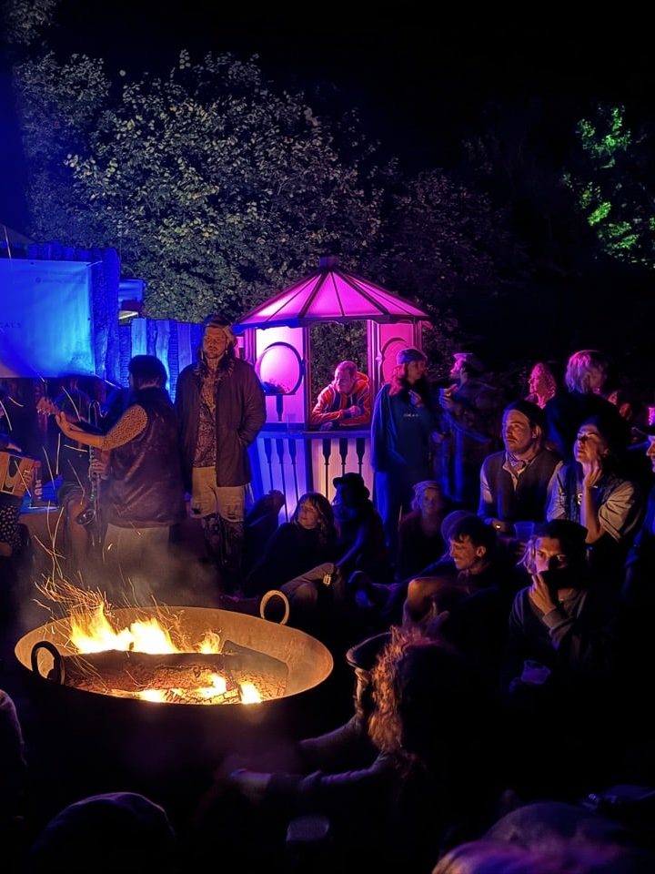 Friends sitting around a campfire at a festival